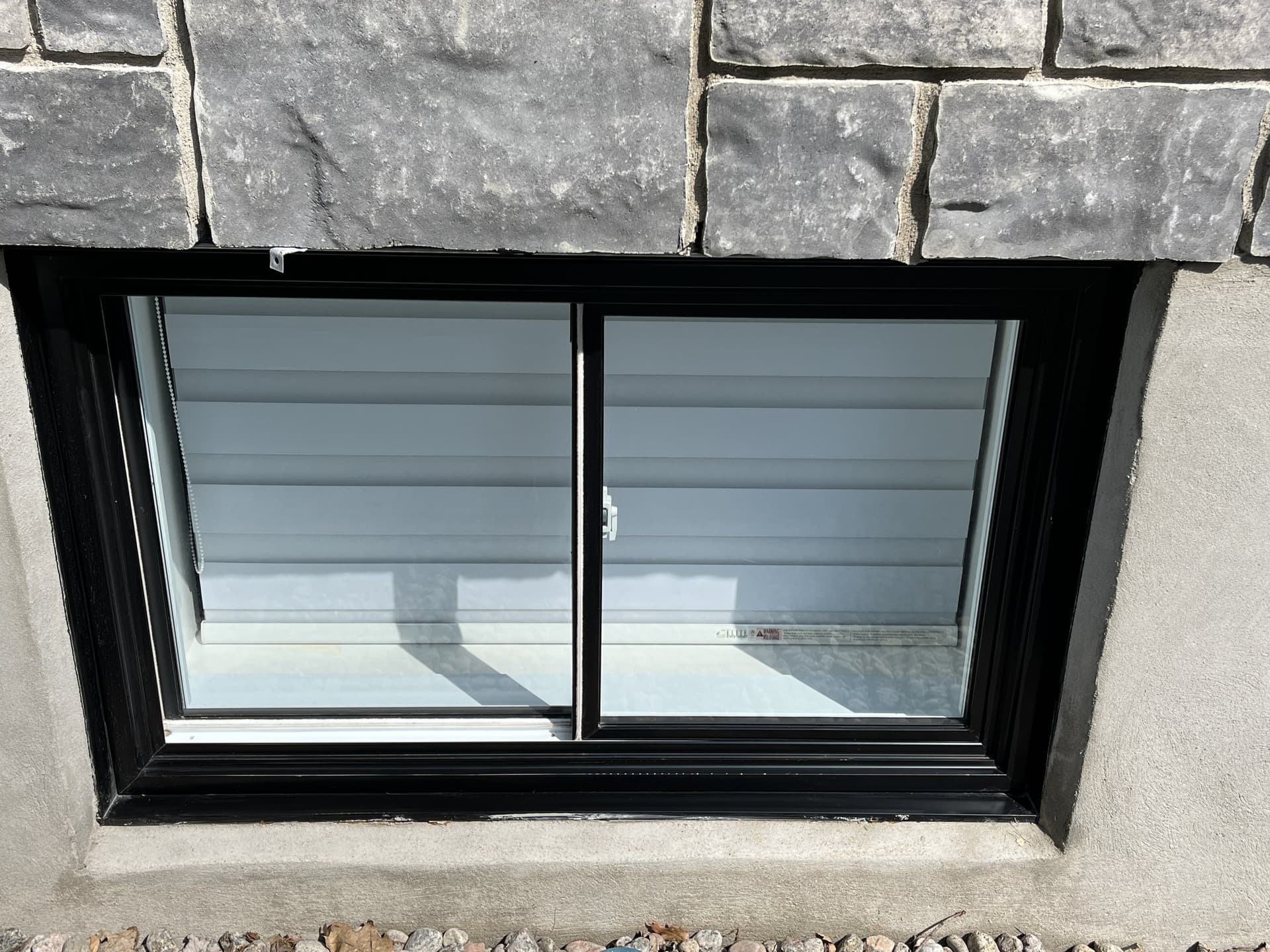 Clean basement window with black frame and horizontal siding