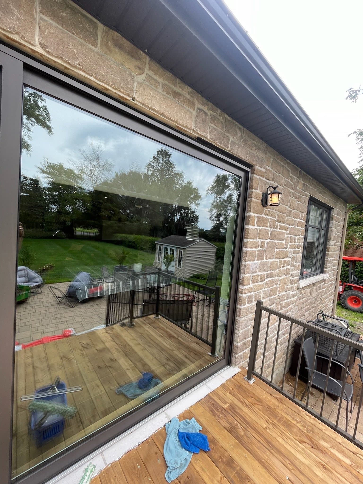 Large glass patio door on a stone house, freshly cleaned with deck and railing visible