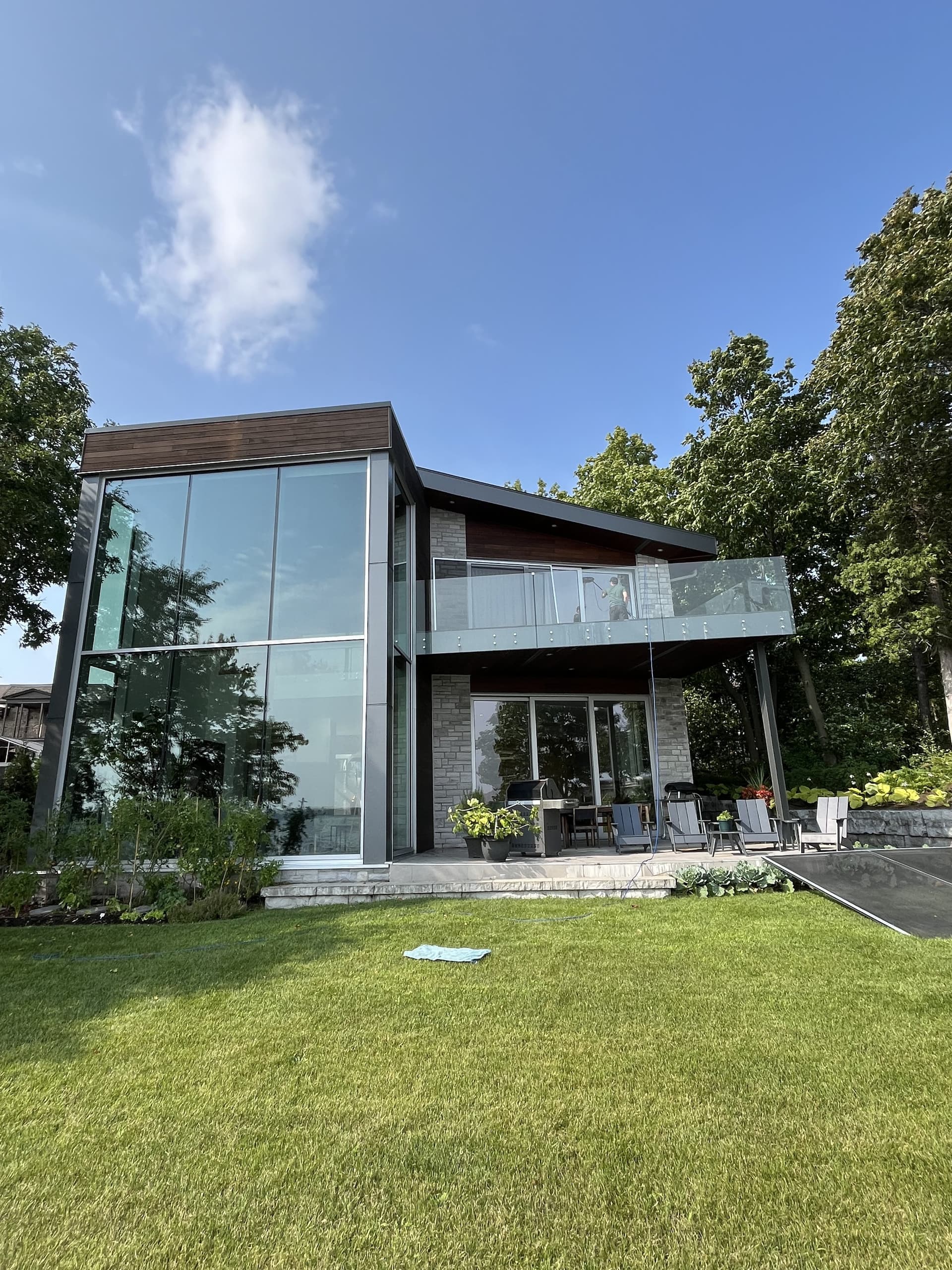 Modern glass house with sparkling clean windows and manicured lawn