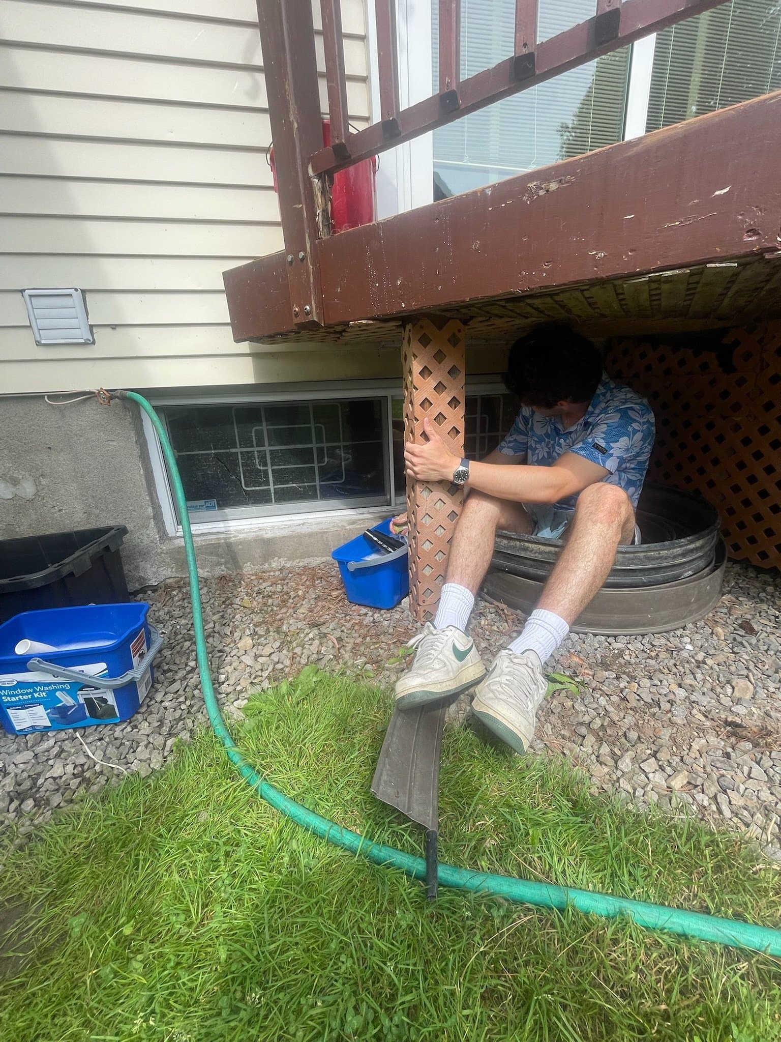 Team member under a deck preparing equipment with tools nearby