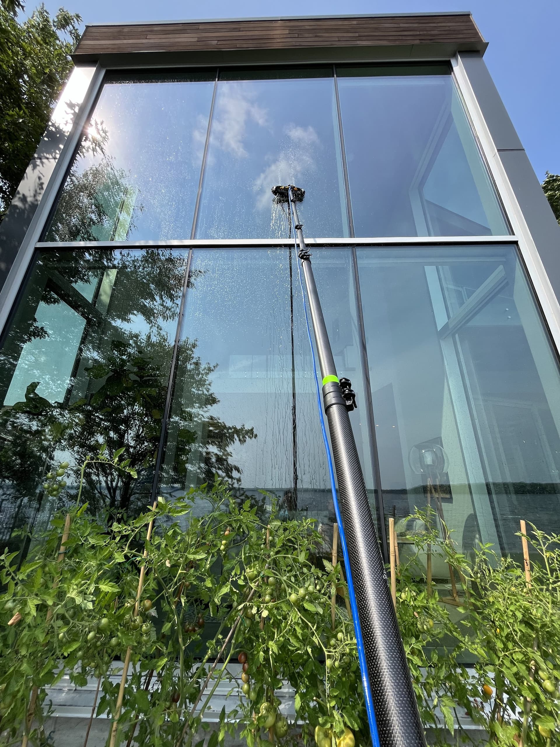Large glass facade being cleaned with a water-fed pole system